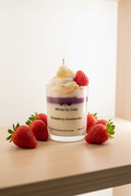Strawberry cheesecake candle with whipped cream and a strawberry on top, branded 'Wicks by Gaby'.

